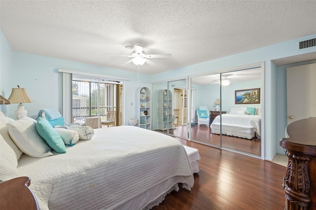 bedroom featuring multiple closets, ceiling fan, dark hardwood / wood-style flooring, and a textured ceiling