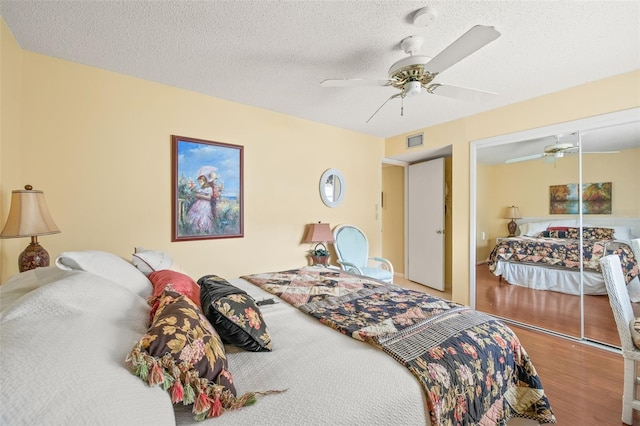 bedroom featuring a closet, wood-type flooring, ceiling fan, and a textured ceiling