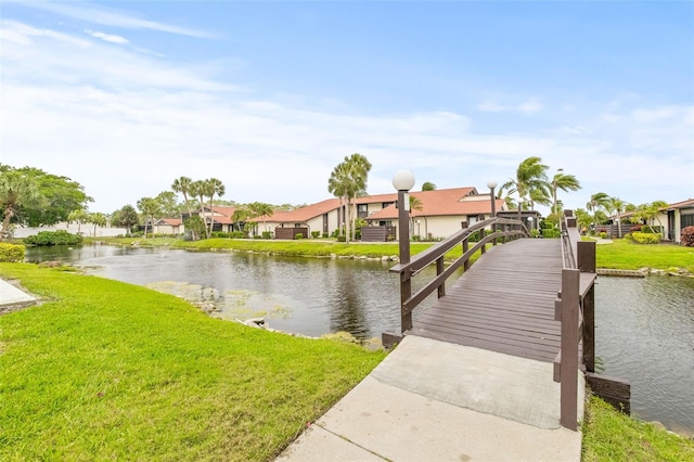 view of dock with a yard and a water view