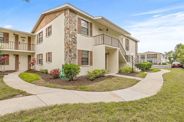 view of property with a front lawn and a balcony