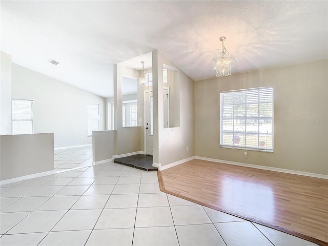 foyer with vaulted ceiling, light tile patterned floors, and an inviting chandelier