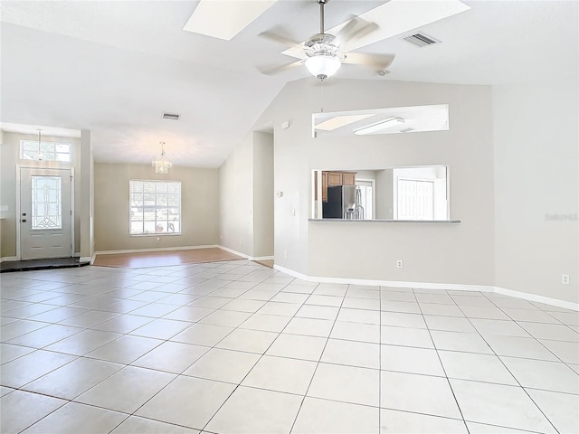 tiled spare room featuring lofted ceiling and ceiling fan with notable chandelier