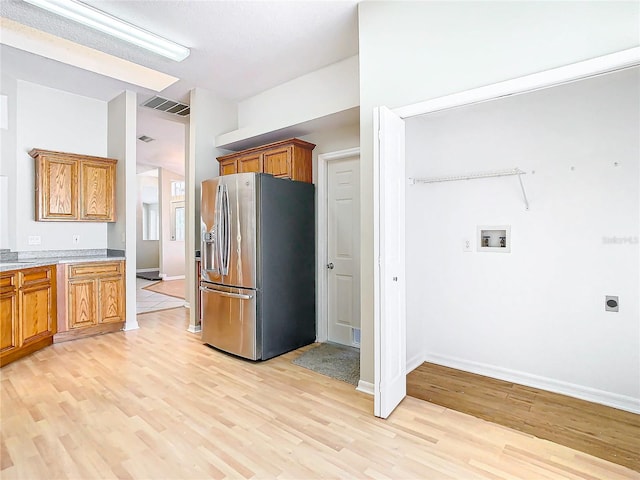 kitchen with light wood-type flooring and stainless steel refrigerator with ice dispenser