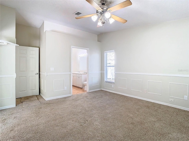 unfurnished bedroom featuring connected bathroom, light carpet, and ceiling fan