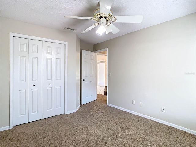 unfurnished bedroom featuring ceiling fan, carpet, a textured ceiling, and a closet