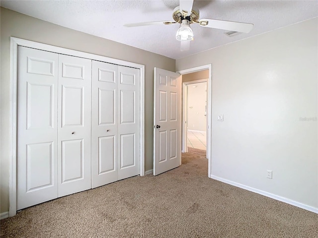 unfurnished bedroom featuring light carpet, a textured ceiling, ceiling fan, and a closet