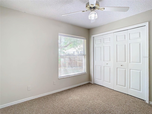 unfurnished bedroom featuring ceiling fan, a closet, carpet floors, and a textured ceiling