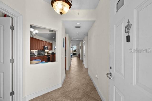 corridor featuring a notable chandelier and light tile floors