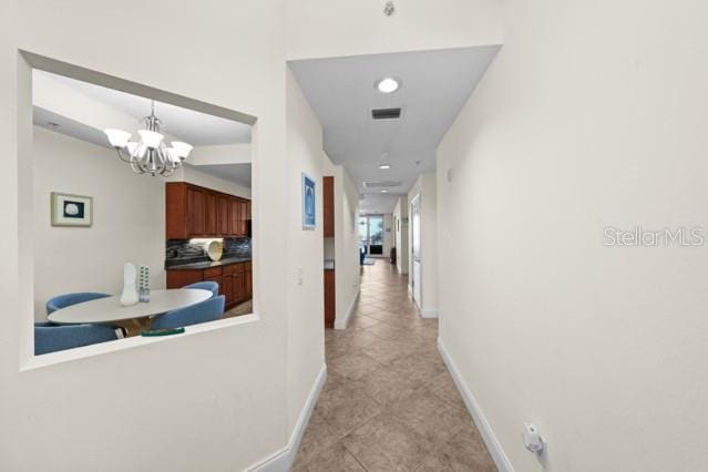 hall with an inviting chandelier and light tile floors