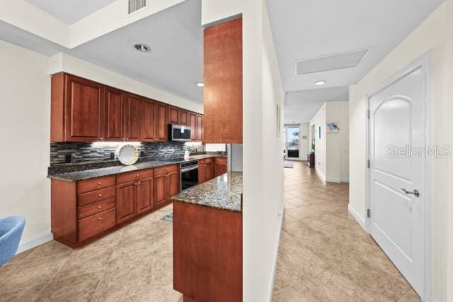 kitchen featuring dark stone counters, backsplash, and light tile floors