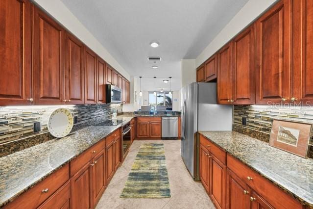 kitchen featuring light tile floors, stainless steel appliances, light stone counters, decorative light fixtures, and tasteful backsplash