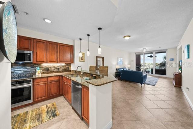 kitchen featuring kitchen peninsula, appliances with stainless steel finishes, sink, ceiling fan, and hanging light fixtures