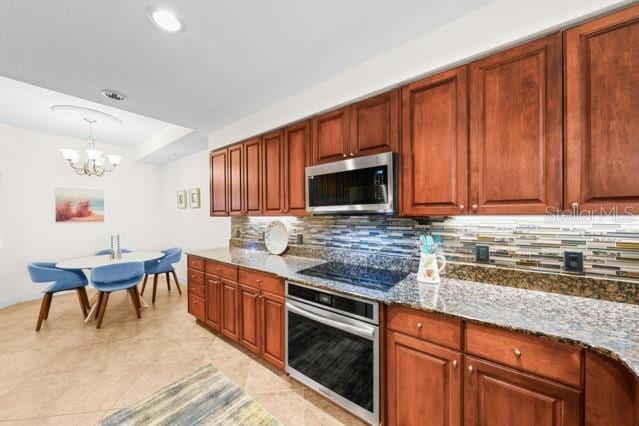 kitchen with an inviting chandelier, tasteful backsplash, dark stone countertops, stainless steel appliances, and light tile flooring