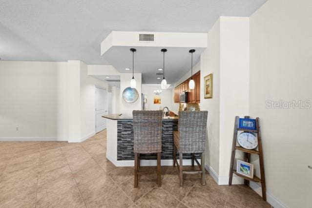 kitchen featuring light tile floors, a kitchen breakfast bar, sink, and hanging light fixtures