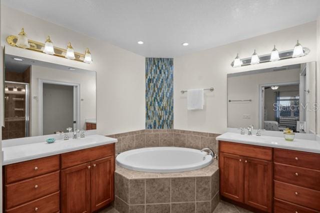 bathroom featuring double sink vanity and tiled bath