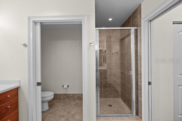 bathroom with walk in shower, tile flooring, toilet, and vanity