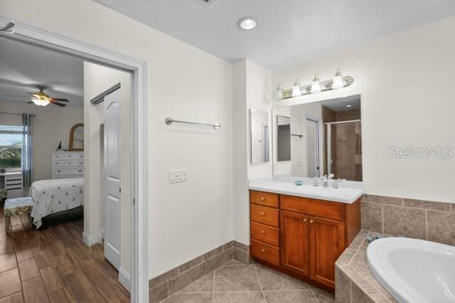 bathroom featuring ceiling fan, tile flooring, separate shower and tub, and vanity