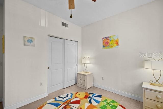 bedroom with light tile flooring, ceiling fan, and a closet