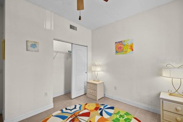 bedroom with ceiling fan, light tile floors, and a closet