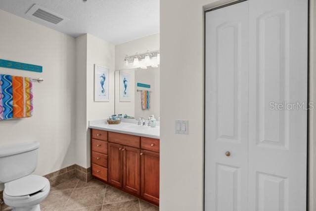 bathroom featuring toilet, vanity, and tile floors