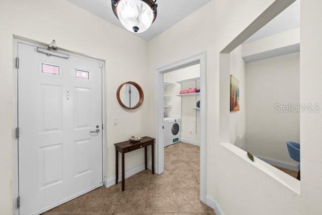 hallway with washer / clothes dryer and light tile flooring