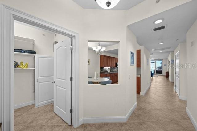 hall with an inviting chandelier and light tile floors