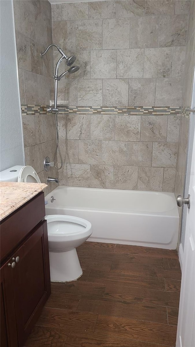 full bathroom featuring tiled shower / bath, toilet, vanity, and wood-type flooring