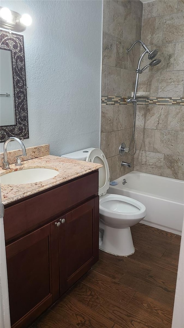 full bathroom with toilet, vanity, tiled shower / bath, and hardwood / wood-style flooring