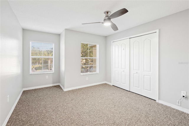 unfurnished bedroom with carpet floors, ceiling fan, a closet, and multiple windows