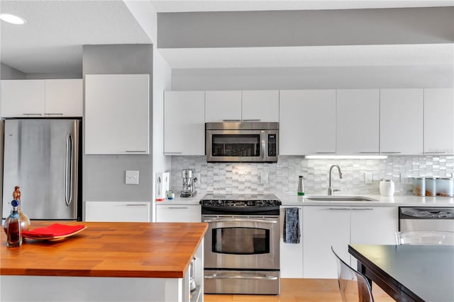 kitchen with white cabinets, decorative backsplash, stainless steel appliances, and sink