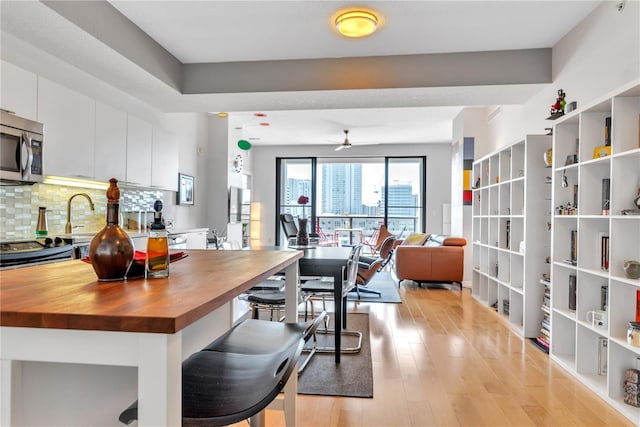 kitchen with wood counters, white cabinets, ceiling fan, tasteful backsplash, and stainless steel appliances