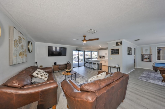 living room with billiards, crown molding, light hardwood / wood-style flooring, a textured ceiling, and ceiling fan