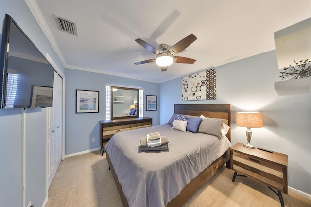 carpeted bedroom featuring ornamental molding, ceiling fan, and a closet