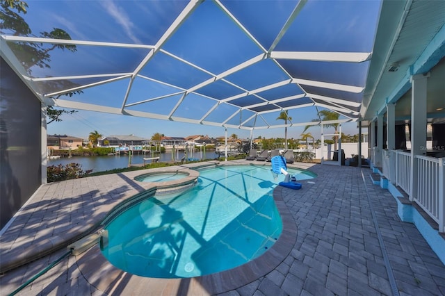 view of pool featuring a patio area, an in ground hot tub, a water view, and glass enclosure