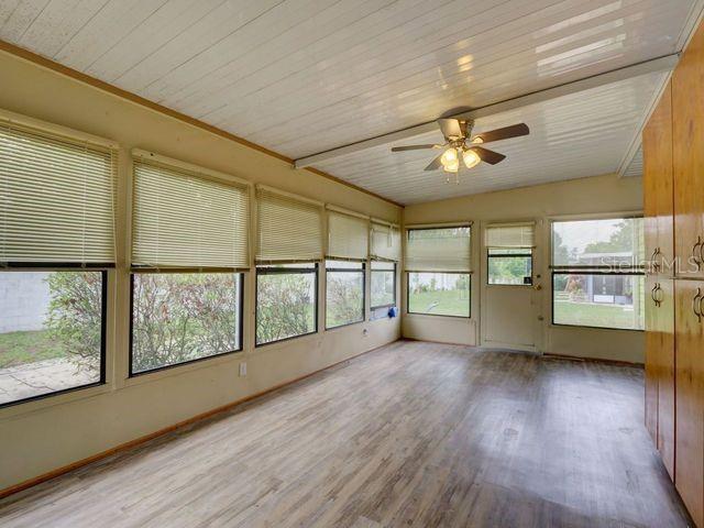 unfurnished sunroom with ceiling fan, a healthy amount of sunlight, and wooden ceiling