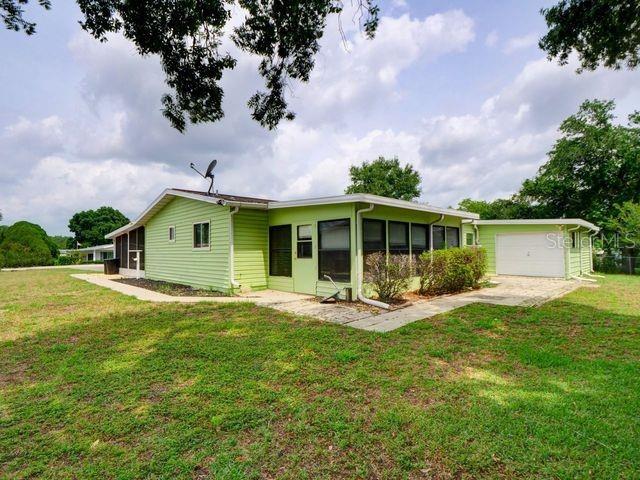 single story home with a sunroom, a front yard, and a garage