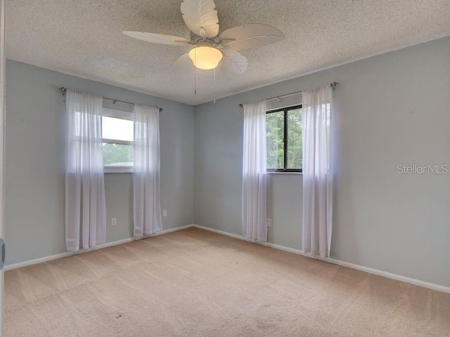 carpeted spare room featuring ceiling fan and a textured ceiling