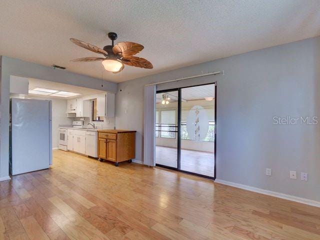 kitchen with a textured ceiling, white appliances, ceiling fan, white cabinets, and light hardwood / wood-style floors