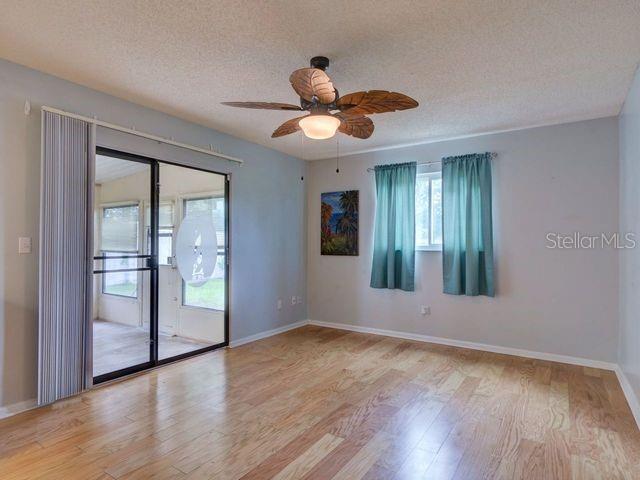 unfurnished room with ceiling fan, a textured ceiling, and light hardwood / wood-style flooring