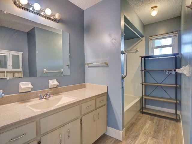 bathroom featuring vanity, hardwood / wood-style floors, a textured ceiling, and shower / bathtub combination