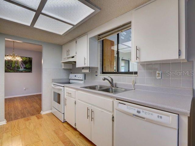 kitchen with white appliances, backsplash, sink, light hardwood / wood-style floors, and white cabinetry