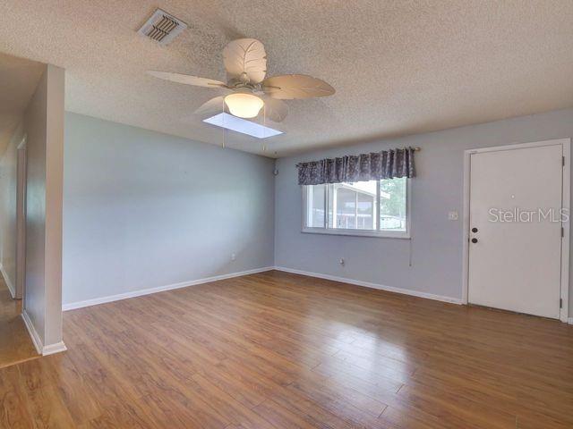 empty room with ceiling fan, a textured ceiling, and hardwood / wood-style flooring