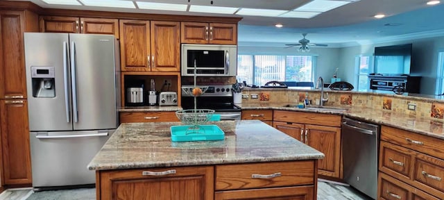 kitchen with light stone counters, ceiling fan, sink, tasteful backsplash, and stainless steel appliances