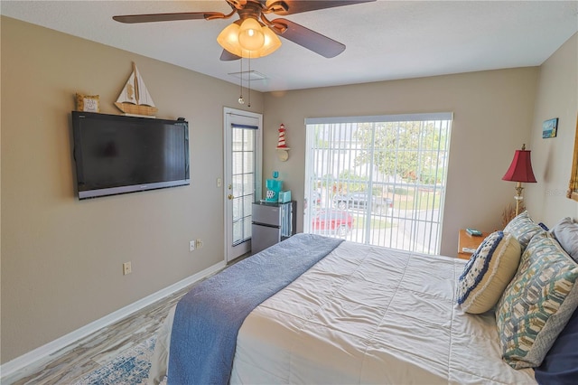 bedroom with access to outside, stainless steel refrigerator, ceiling fan, and hardwood / wood-style floors