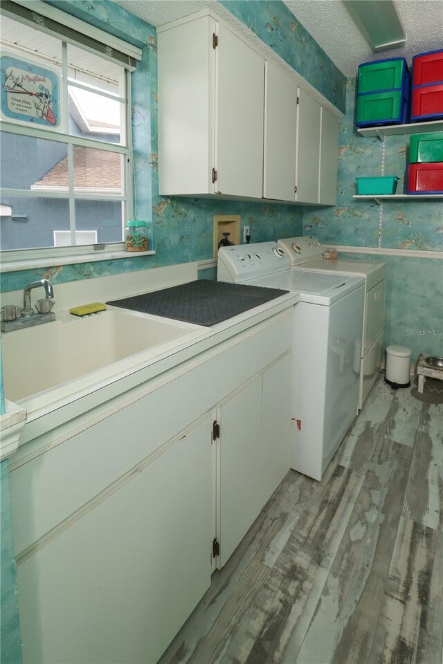 clothes washing area featuring separate washer and dryer, hookup for a washing machine, sink, cabinets, and a textured ceiling