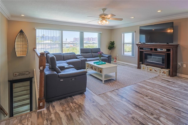 living room featuring hardwood / wood-style floors, ornamental molding, ceiling fan, and a wealth of natural light