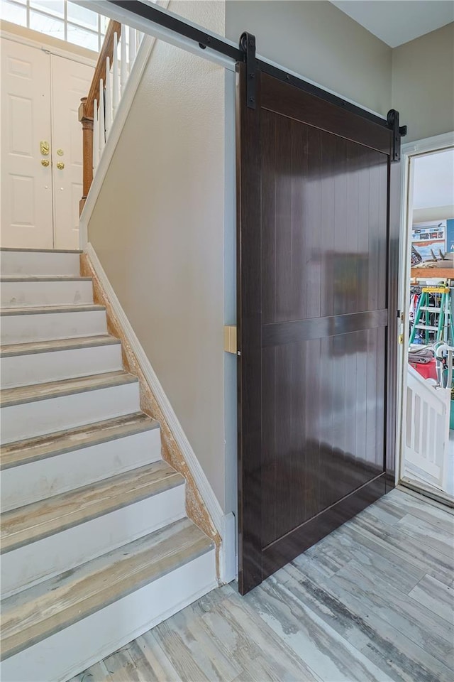 stairs featuring a barn door and wood-type flooring