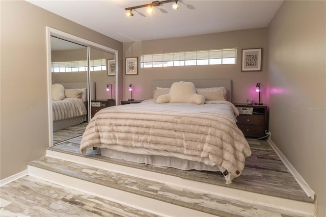 bedroom featuring rail lighting, a closet, and hardwood / wood-style flooring