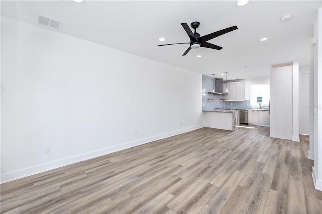 unfurnished living room featuring ceiling fan, sink, and light wood-type flooring