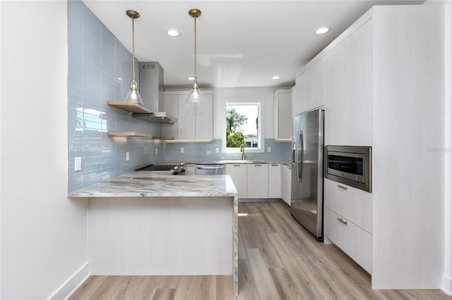 kitchen featuring white cabinets, decorative light fixtures, kitchen peninsula, and appliances with stainless steel finishes